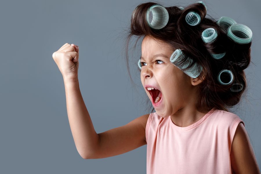 little girl shakes fist angrily with rollers in hair